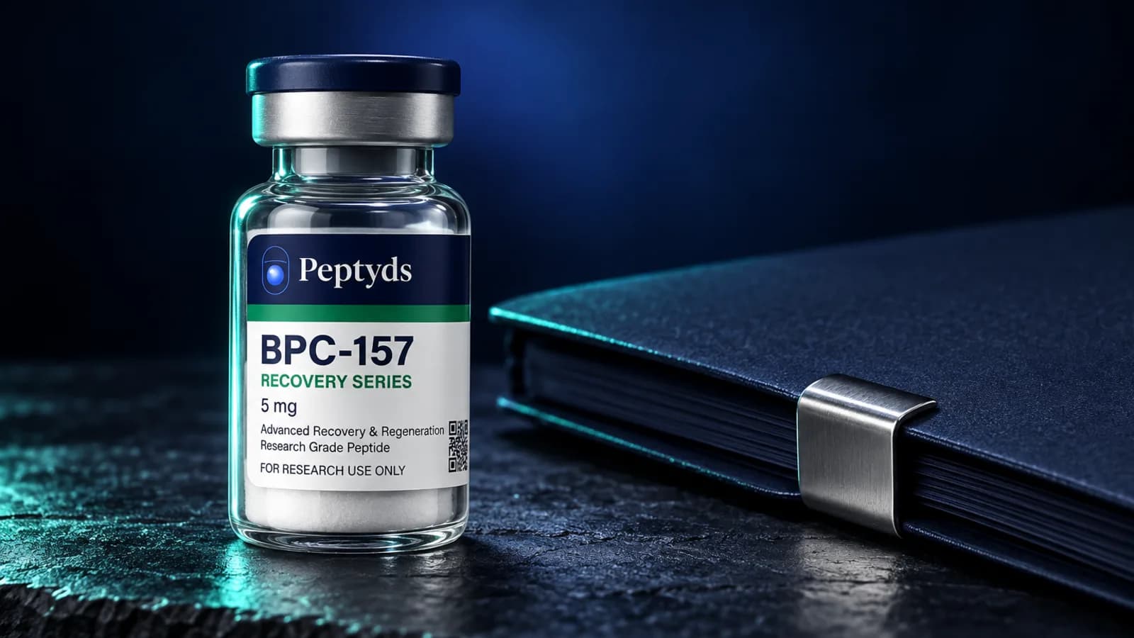 Ein Peptyds-Forschungsvial mit der Aufschrift "BPC-157, Recovery Series, 5 mg" neben einem geschlossenen marineblauen Notizbuch mit Metallverschluss.