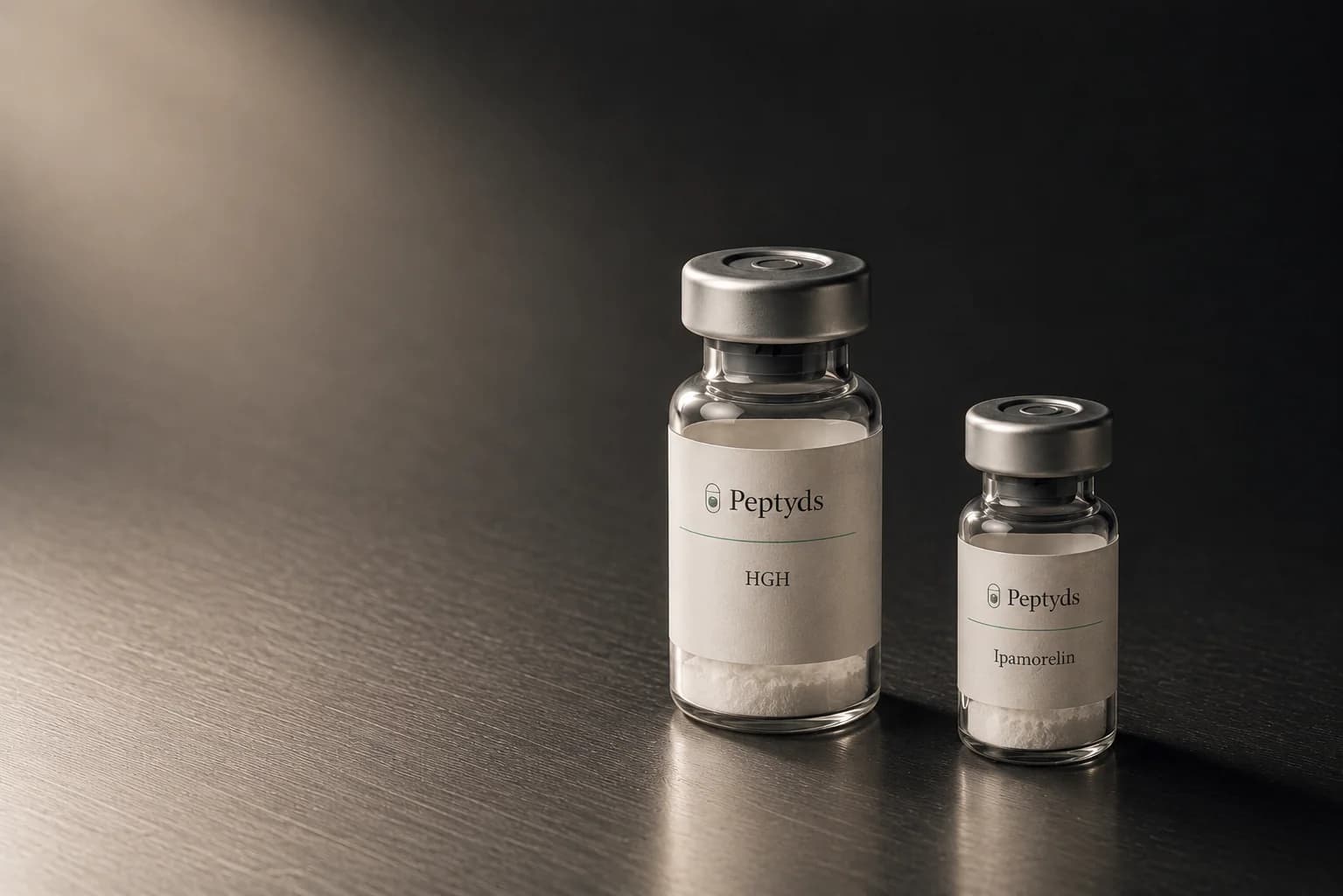 Zwei Peptyds-Forschungsvials auf einer dunklen gebürsteten Metallbank, ein höheres HGH-Vial neben einem kleineren Ipamorelin-Vial, von links oben beleuchtet